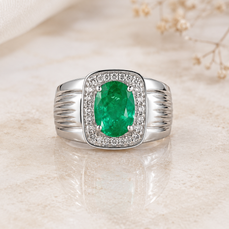 Silver ring with an oval emerald center surrounded by a halo of diamonds on a beige surface.