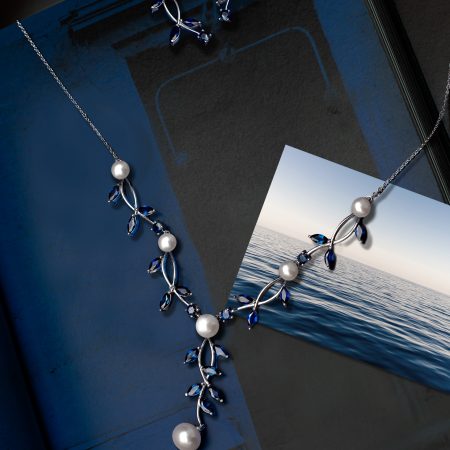 Blue and silver jewelry set with pearl accents displayed on a dark blue background. Includes dangling earrings and a matching necklace.