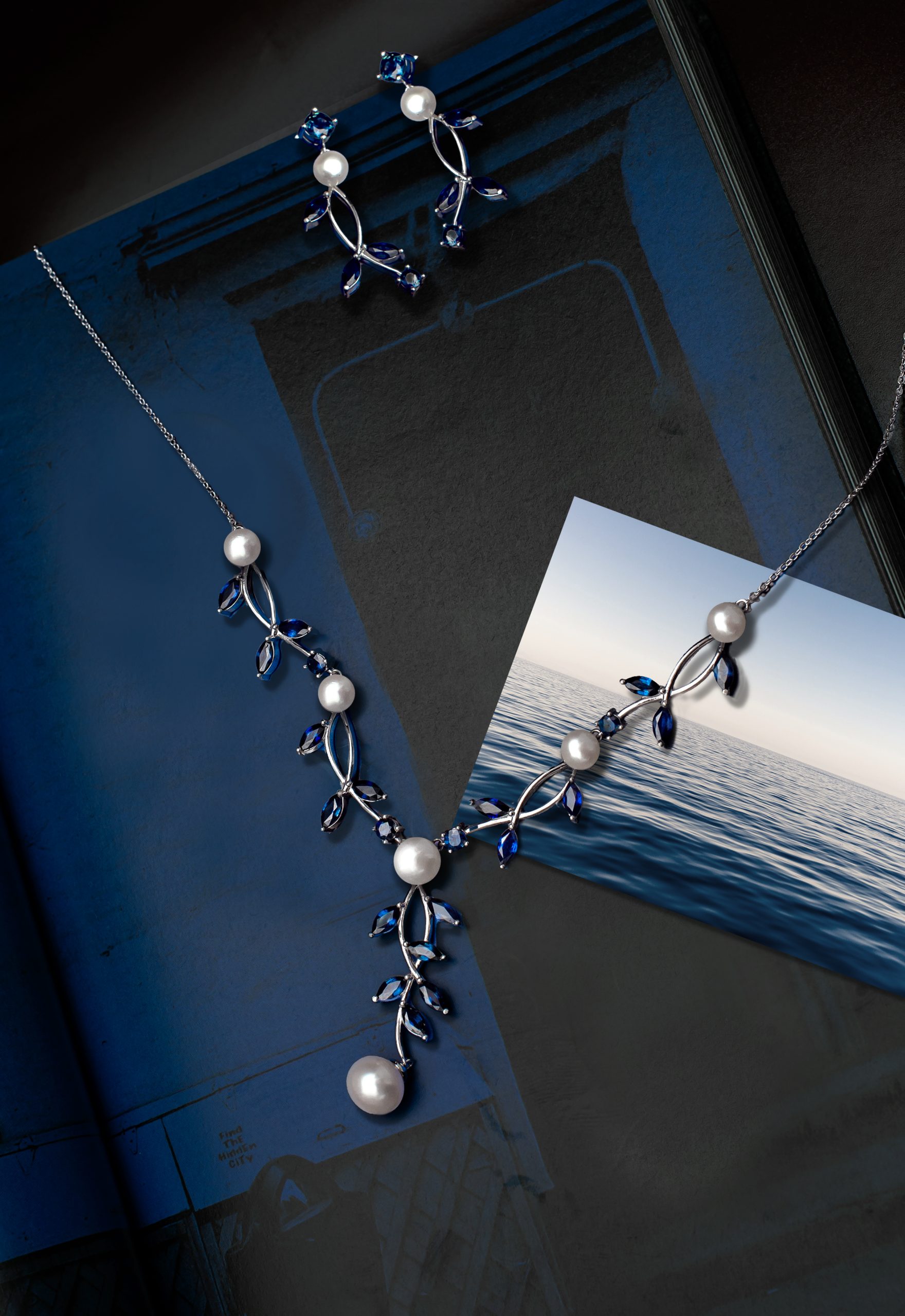 _NZR2178f Blue and silver jewelry set with pearl accents displayed on a dark blue background. Includes dangling earrings and a matching necklace.