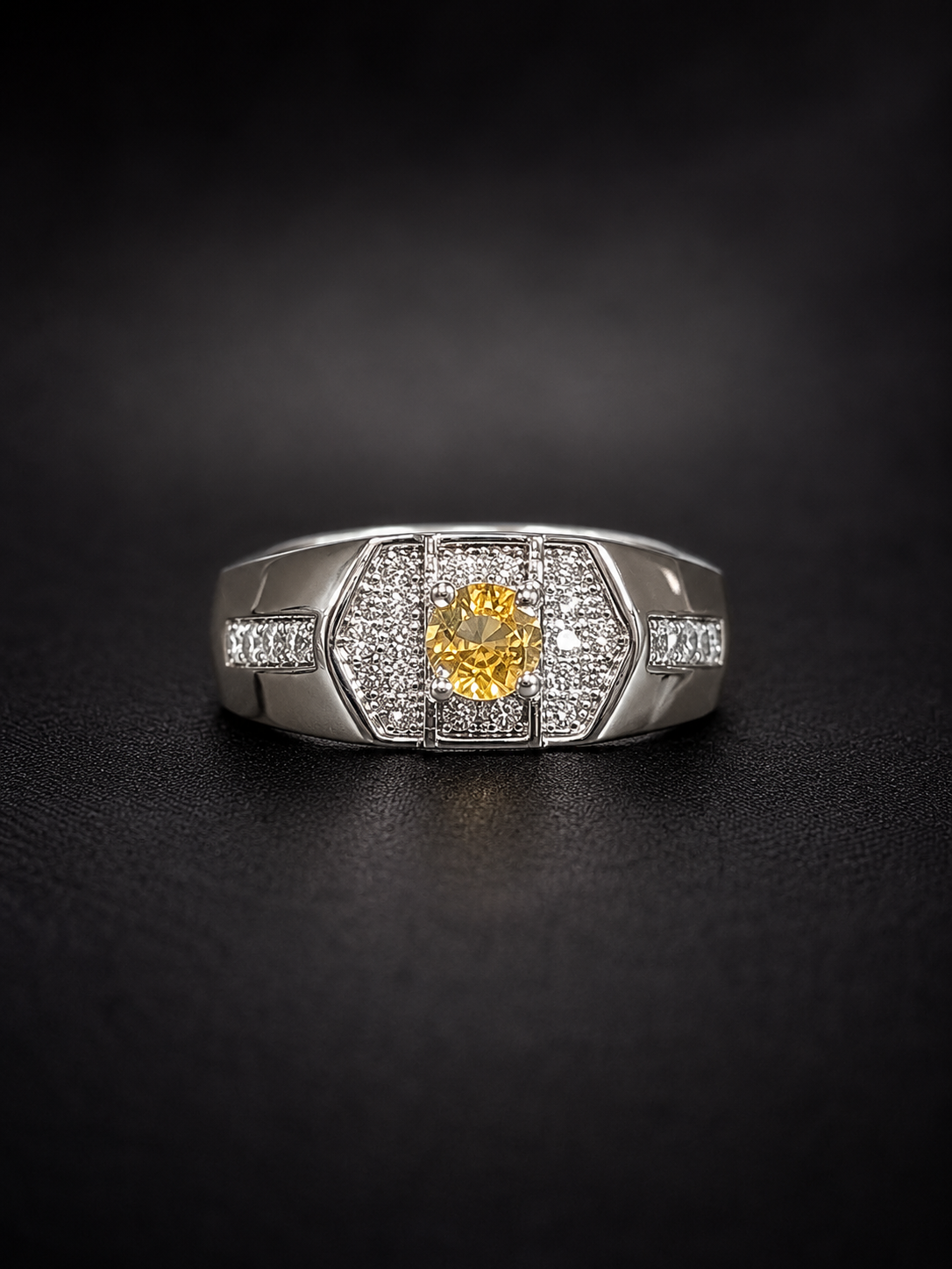 Yellow-Sapphire-Ring Silver ring with a yellow central gemstone surrounded by pave diamonds on a black background.