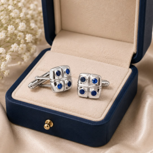 Pair of silver cufflinks with four blue stones in an open navy jewelry box.