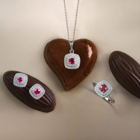 Diamond-studded heart pendant on a silver chain resting on a chocolate heart.
