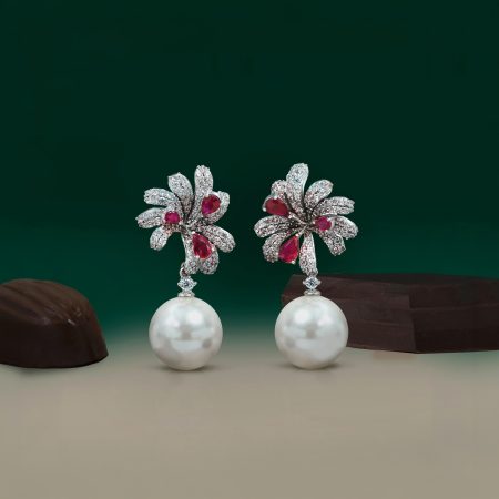 Diamond-and-ruby floral brooches with pearls on a dark green background.