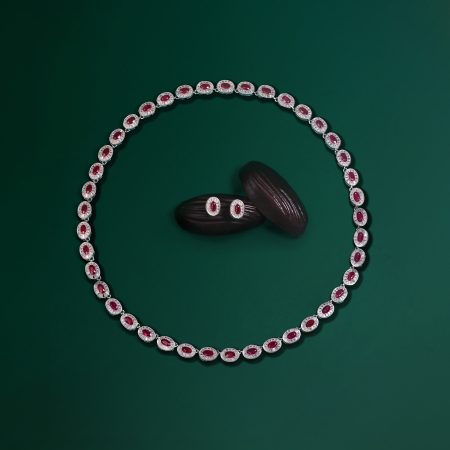 Necklace with red gemstones encircled by diamonds on a green background.